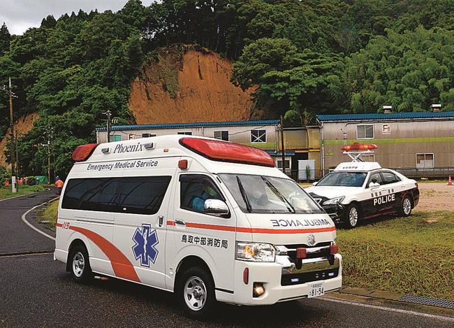 土砂崩れの現場(写真奥)から救出した人を搬送する救急車=8日午後6時43分、倉吉市大原