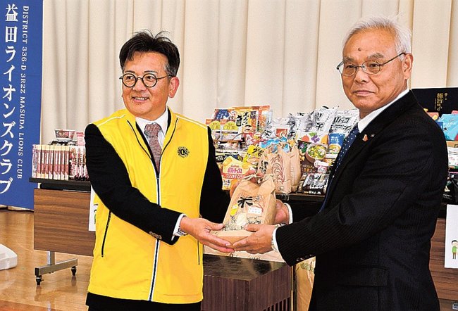 集めた食品を末成弘明会長(右)に手渡す橋本隆幸会長=益田市須子町、市総合福祉センター