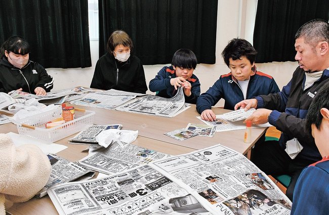 新聞から気になる写真を探す生徒＝松江市西川津町、島根県立松江養護学校