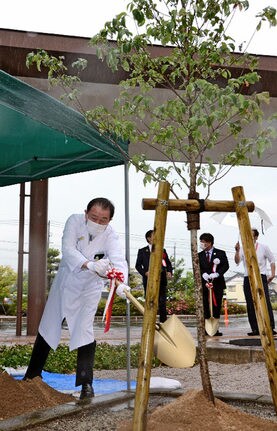 ハナミズキの根元に土をかける杉山章病院事業管理者=出雲市灘分町、市立総合医療センター