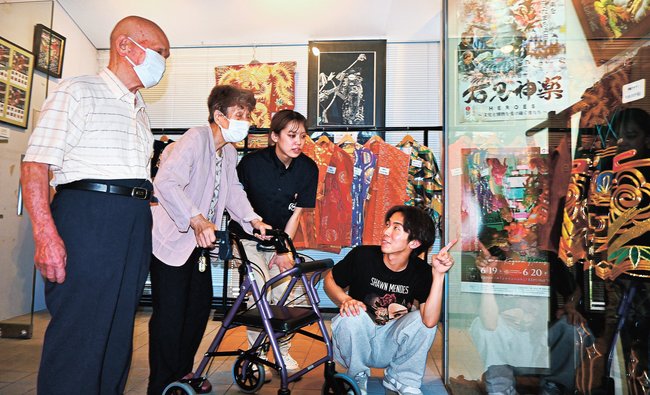 施設利用者に神楽衣装を紹介する学生（右端）＝浜田市金城町下来原、神楽ショップくわの木