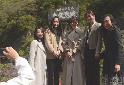 研修で立久恵峡をバックに記念撮影する客室乗務員=出雲市乙立町