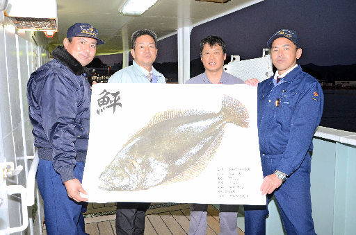 ヒラメを釣った神海丸の甲板で魚拓を広げる関係者＝島根県隠岐の島町の西郷港