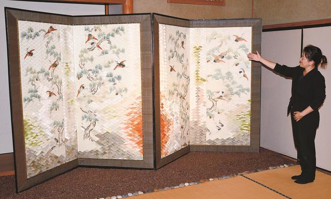 松の周りを鶴が華やかに舞う様子を表現した「風の祈り」を紹介するスタッフ＝出雲市斐川町福富、出雲キルト美術館