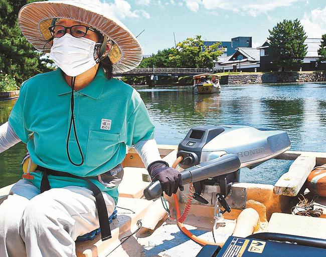 試作型の小型電動推進機を搭載した遊覧船を操縦する船頭＝松江市北堀町