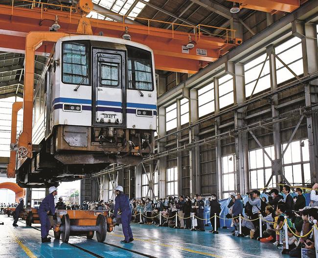 クレーンによる電車のつり上げ作業を見学する来場者=米子市日ノ出町２丁目、後藤総合車両所