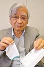 着脱テープを付けた不織布マスクと、マスクガーゼを手にする井上貴央施設長＝米子市内