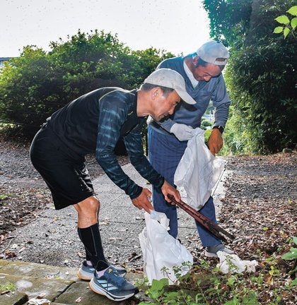 石段の脇に落ちていたごみを拾う会員＝出雲市小境町