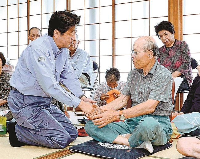 記録的豪雨で大きな被害が出た島根県津和野町の避難所を訪れ、被災者らを激励する安倍晋三首相（当時）＝２０１３年８月４日