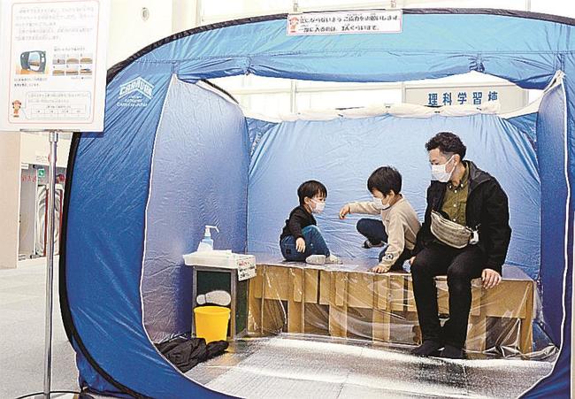 屋内用テントと段ボールベッドの使い心地を確かめる来館者＝出雲市今市町、出雲科学館