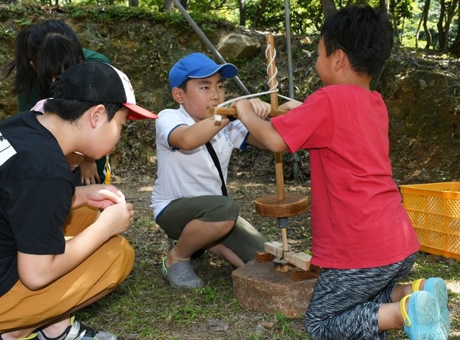 二人一組で火おこしに挑戦する児童=島根県美郷町村之郷、蟠龍峡公園