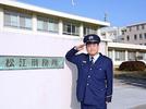 正門前で敬礼し「みんなが安心して暮らせる社会づくりに役立つ仕事だ」と刑務官のやりがいを語る森中さん＝松江市西川津町の松江刑務所