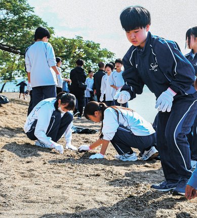 宍道湖岸の砂浜を清掃する松徳学院中学校の生徒たち=松江市岡本町