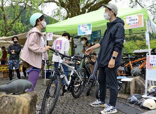町内のイベントで、電動アシスト付き自転車のツアーをＰＲする協議会のメンバー（右）＝島根県津和野町後田、鷺舞モニュメント広場