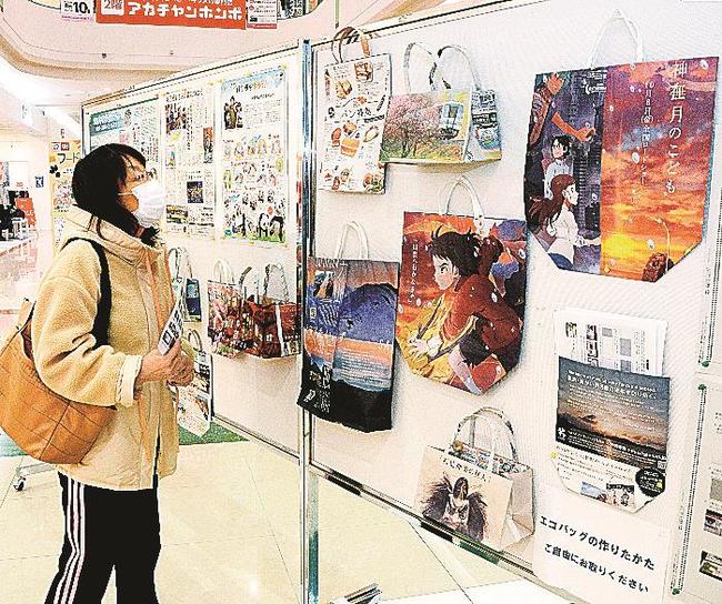 新聞紙で作られたエコバッグを見つめる来館者＝出雲市大塚町、ゆめタウン出雲