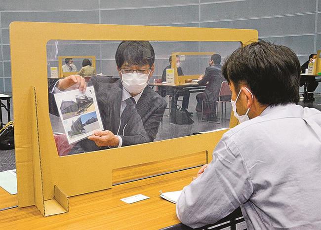 高校の進路指導担当者（右）に事業内容を説明する企業の採用担当者＝松江市学園南１丁目、くにびきメッセ