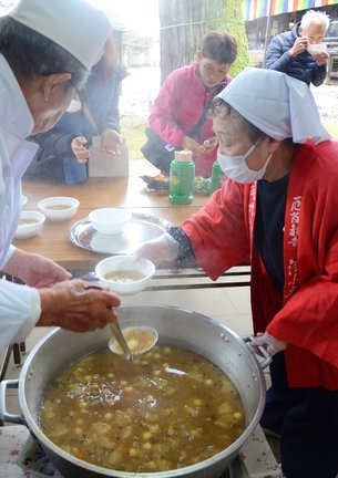 権現粥をよそい参拝者に振る舞う関係者＝安来市清水町、清水寺