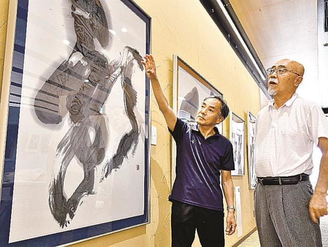 二人展の会場で、渡辺剛さん（左）の書作品を味わう金築直久さん＝江津市江津町、パレットごうつ