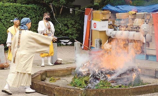護摩壇にちょうちんを投げ入れる福田快宥住住職（左）＝出雲市斐川町阿宮、延命寺
