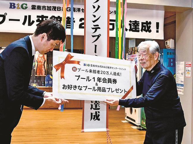 記念品の目録パネルを受け取る井龍末治さん（右）＝雲南市加茂町宇治、同市加茂Ｂ＆Ｇ海洋センター
