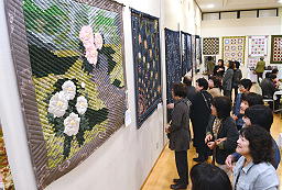 鮮やかに表現されたタペストリーを見る来場者