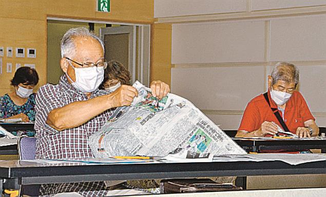新聞を細くちぎっていくゲームを楽しむ参加者＝出雲市湖陵町二部、湖陵コミュニティセンター