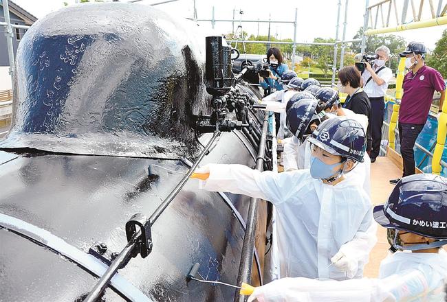 蒸気機関車の胴体部分にペンキを塗る児童＝出雲市大社町北荒木、ＪＲ旧大社駅