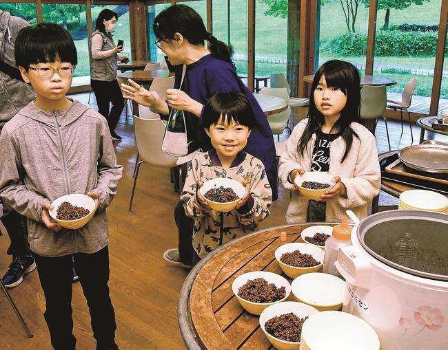 赤米と黒米の入ったご飯を手にする参加者=出雲市斐川町神庭、荒神谷博物館