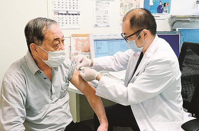 通常診療の合間に新型コロナワクチンを接種する診療所の医師（右）。問診や接種、接種後の経過観察など必要な対応は多く、これ以上の接種数増は難しい＝松江市春日町、たにむら内科クリニック