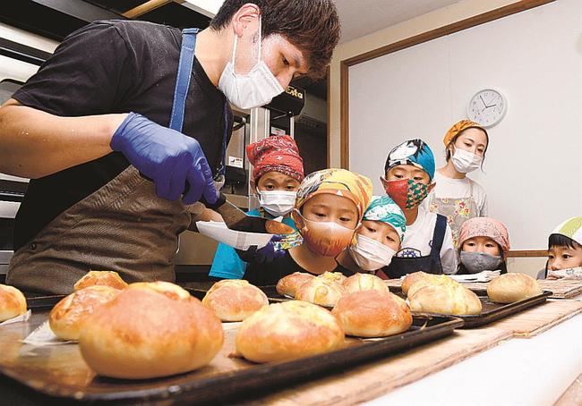 林光さん(左)に教わりながら作り、焼き上がったパンを眺める子どもたち=島根県邑南町山田、パンとサンドイッチの店ルル