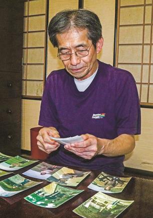 妻・泰子さんとの思い出の写真をみる荒川勉さん＝米子市祇園町２丁目