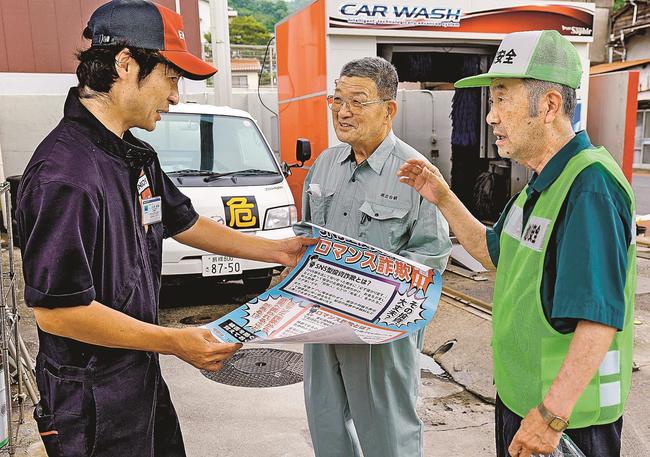 ガソリンスタンドの店員（左）に啓発ポスターの掲示を依頼する参加者＝島根県川本町川本