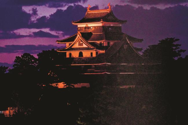 赤色の赤十字カラーにライトアップされた松江城天守＝松江市殿町