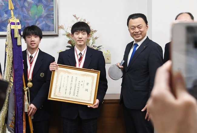 丸山知事と記念撮影に納まる小野主将（左）と黒田選手（左から２人目）