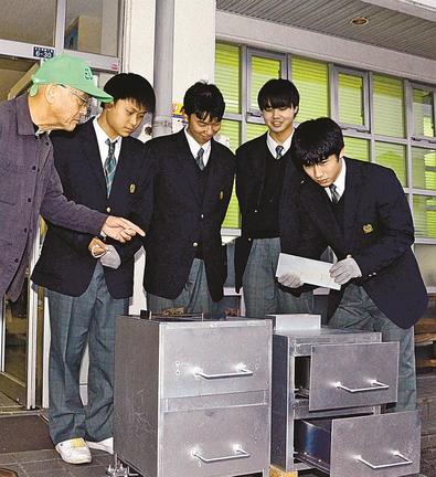 焼き芋製造機の使い方を説明する松江工業高校の生徒=松江市古志原4丁目、古志原公民館