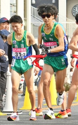 鳥取の２区亀井琥太郎（左）からたすきを受けて走り出す３区風岡永吉＝第２中継所