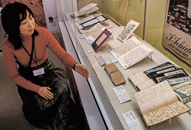 セツの英単語帳や家族間の手紙を紹介する学芸員の門脇実花子さん(左)=松江市奥谷町、小泉八雲記念館