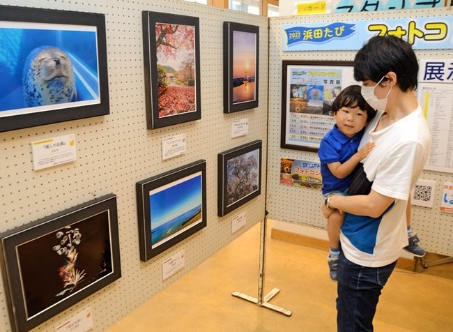 美しい景色を撮影した作品を眺める来場者＝浜田市原井町、道の駅ゆうひパーク浜田
