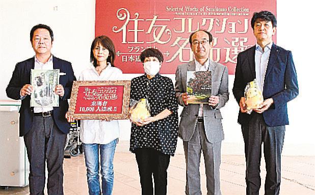 １万人達成の記念撮影に納まる栗本恭子さん（左から２人目）と石見啓子さん（同３人目）ら＝松江市袖師町、島根県立美術館