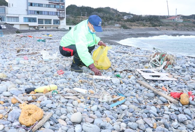 漂着した固形物を拾う住民=益田市高津町、持石海岸