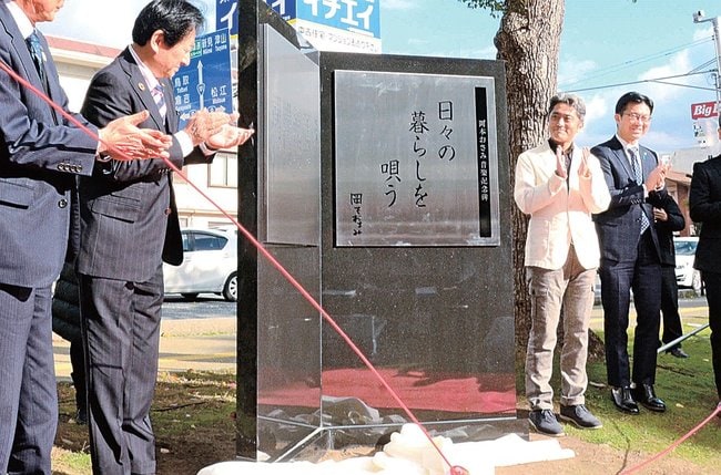 岡本おさみ音楽記念碑の完成を祝う長男の岡本邦彦さん（右から２人目）ら関係者＝米子市角盤町２丁目、市公会堂前