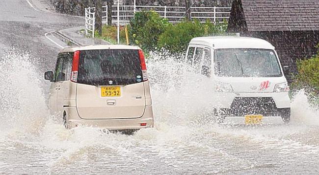 大雨で冠水した道路を走る自動車＝９日午前１０時５６分、島根県隠岐の島町城北町