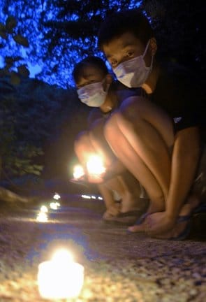 参道に置かれた送り火の明かりを楽しむ子どもたち＝松江市外中原町、月照寺