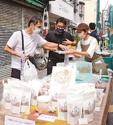 試食を勧めて特産品を売り込む出店者＝東京都大田区、大岡山北口商店街