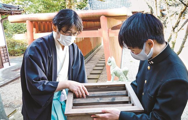 制作したさい銭箱を花田英己宮司(左)に手渡す佐藤龍之介さん=出雲市上塩冶町、塩冶神社
