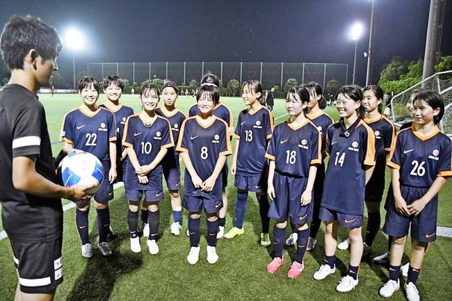 高橋知也監督（左）からアドバイスを受けるディオッサ出雲ＦＣユースの選手たち＝出雲市矢野町、出雲健康公園多目的運動場