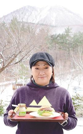 三瓶わさびバーガー（右）とわさびマヨネーズを手にする吉田真由美さん＝大田市三瓶町