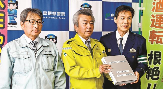 安全運転と安全行動の誓約書名簿を手にするフクダの高橋務常務（中央）と三浦祐明署長（右）＝出雲市塩冶有原町２丁目、出雲署