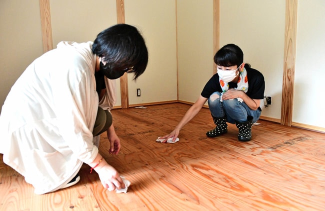 自宅が浸水し、畳を上げて床板をふく住民=15日午後2時49分、江津市桜江町川越地区の田津集落