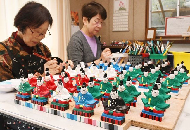 出雲五色天神を一体ずつ丁寧に色付けするメンバー=出雲市斐川町出西